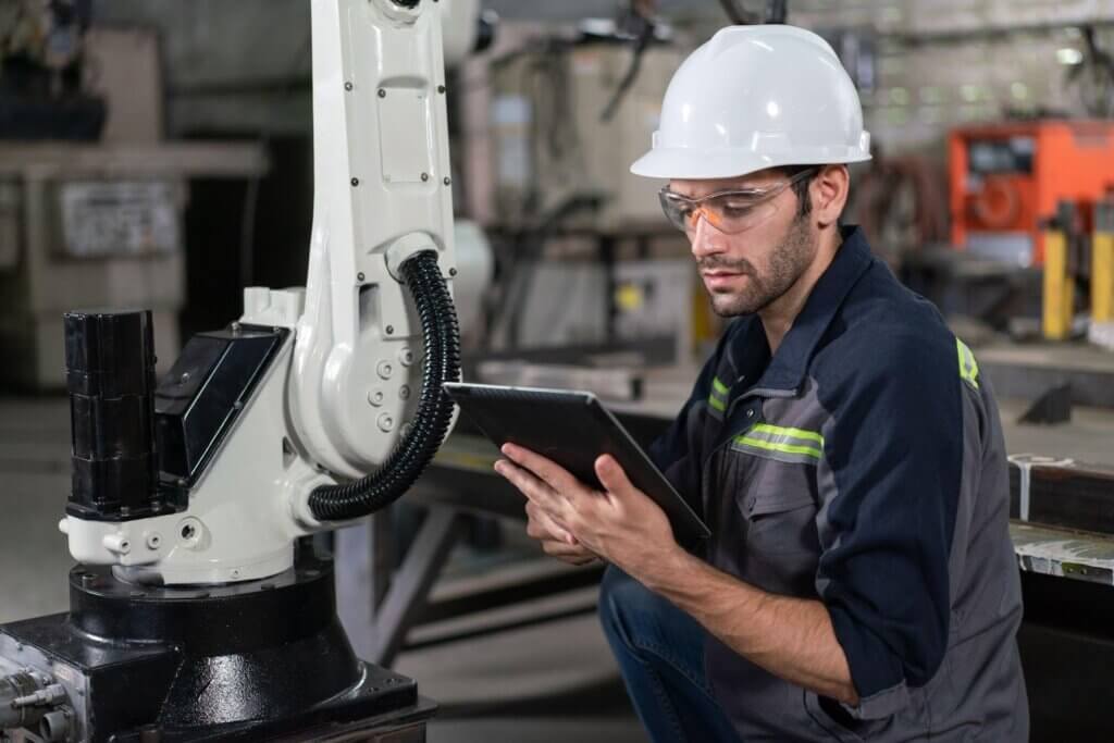 Engenheiro mecânico revisando dados em tablets durante inspeção industrial com robô industrial na fábrica